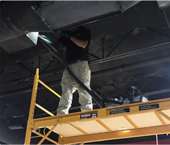 Team member cleaning soot from ceiling.